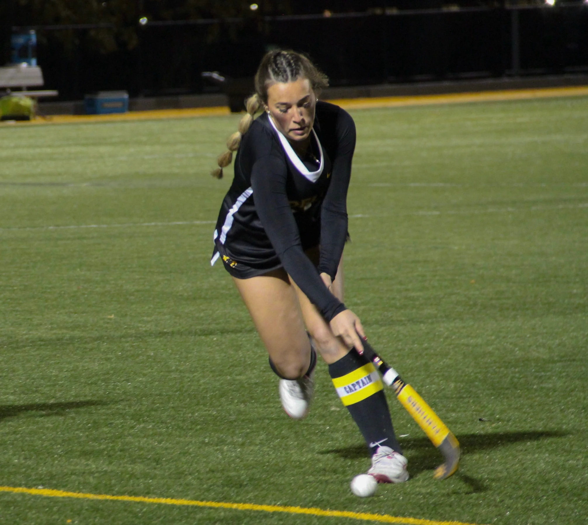 Field hockey player running with the ball during a night game