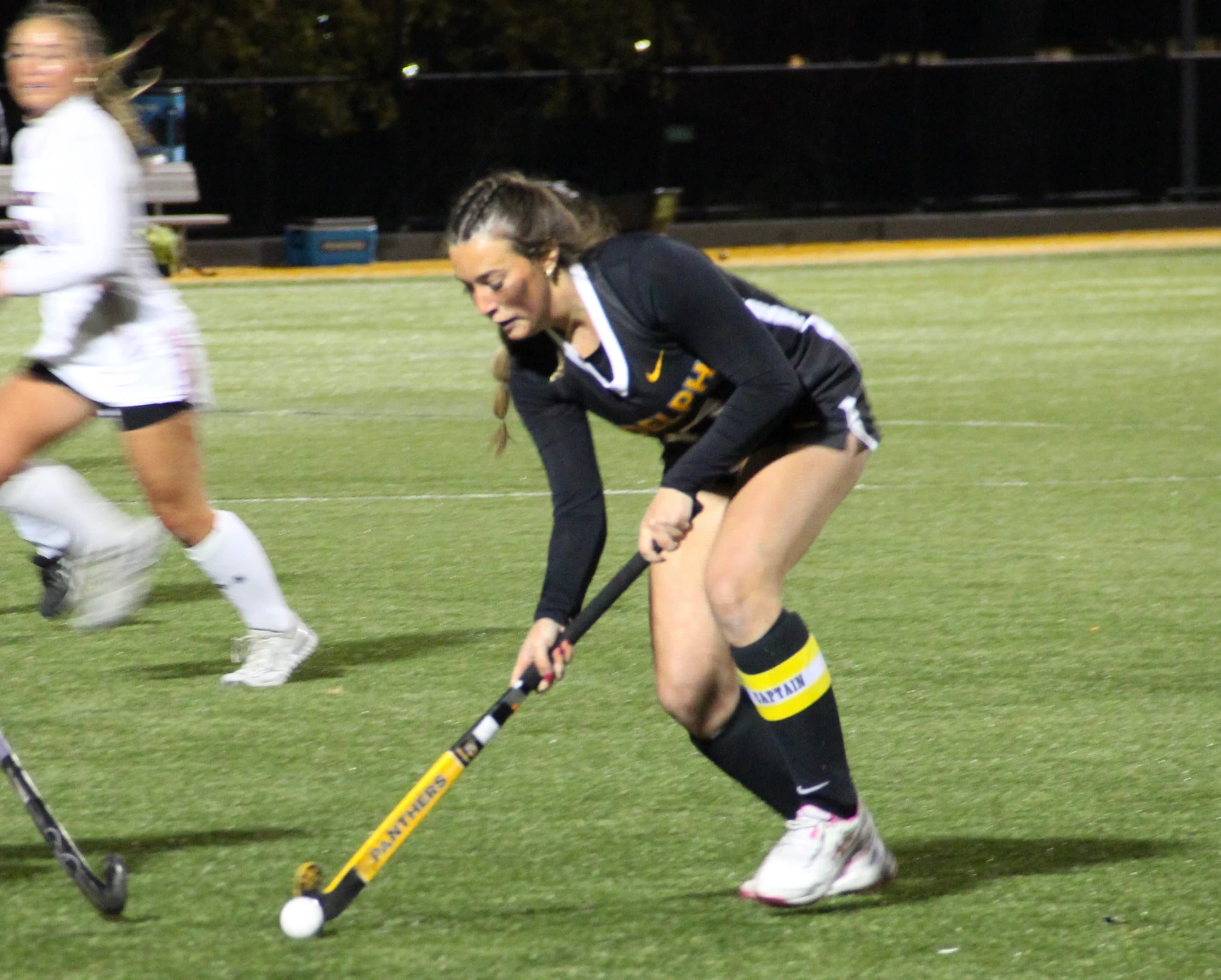Close-up of a field hockey stick and ball on a green turf field