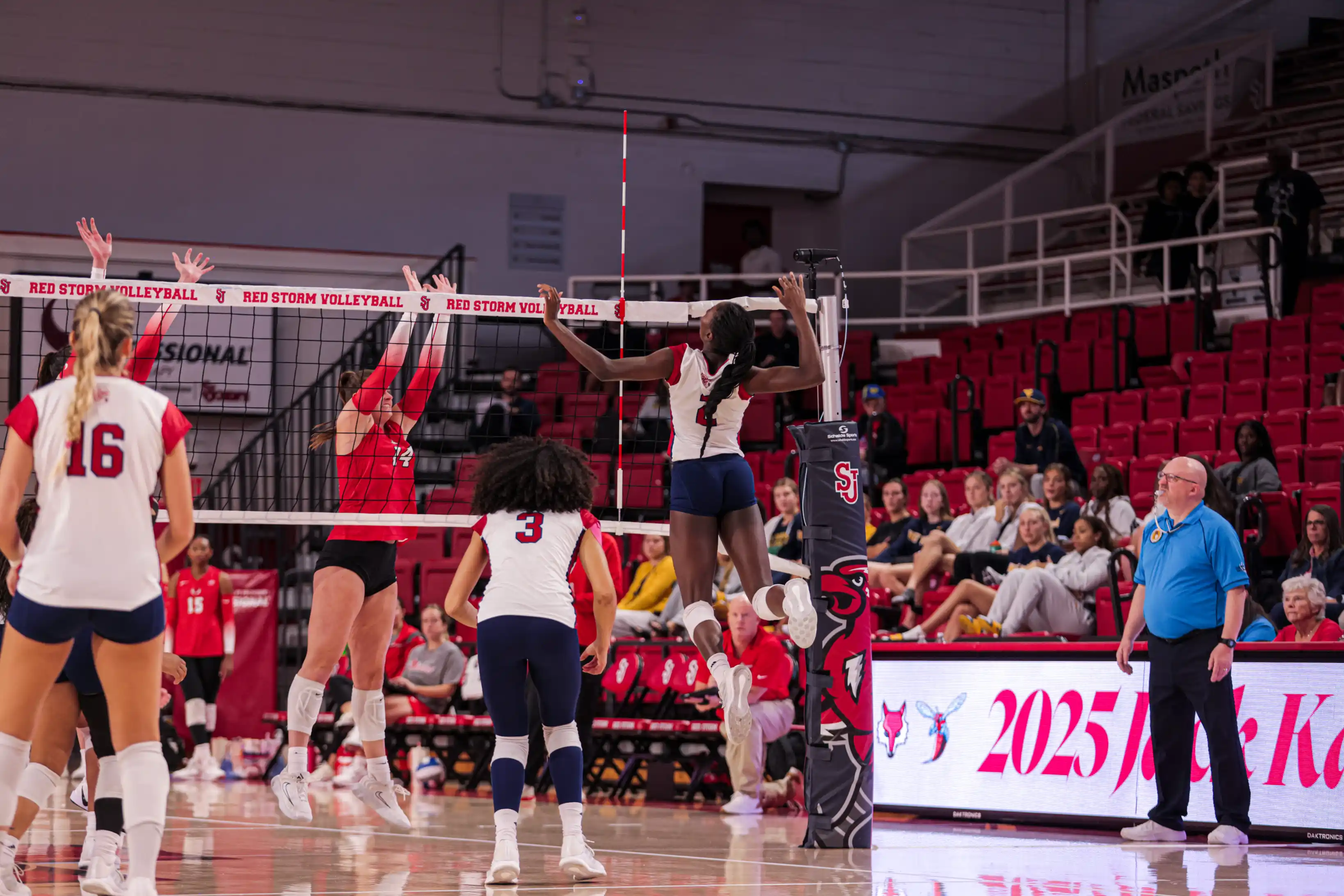 Volleyball players competing at the net during an intense collegiate match